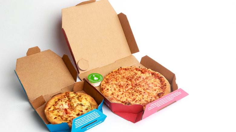 Two sizes of Domino's pizza in boxes on white background