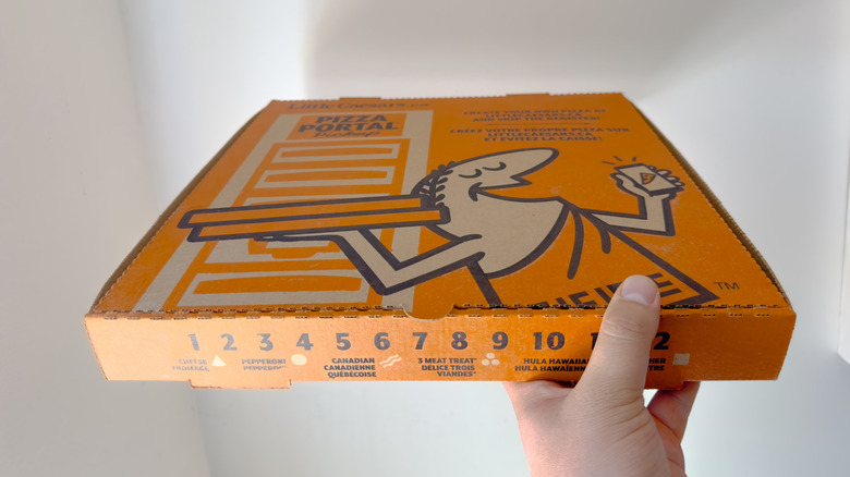 Hand holding box of Little Caesar's pizza