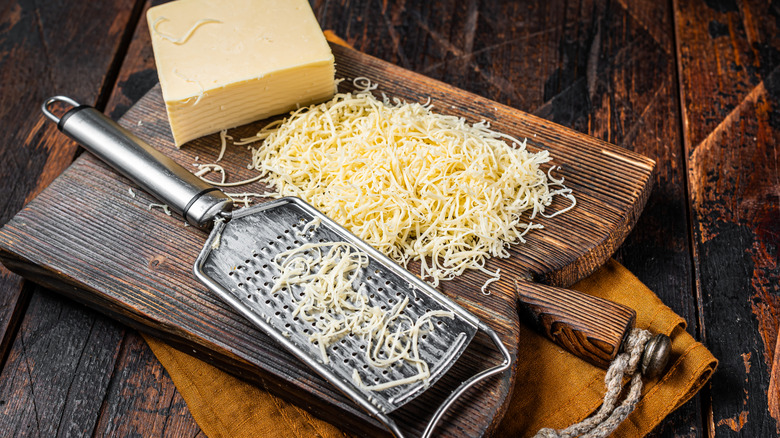 Shredded white cheddar cheese on cutting board