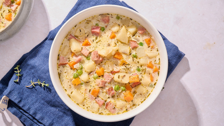 Bowl of ham and potato soup on blue linen