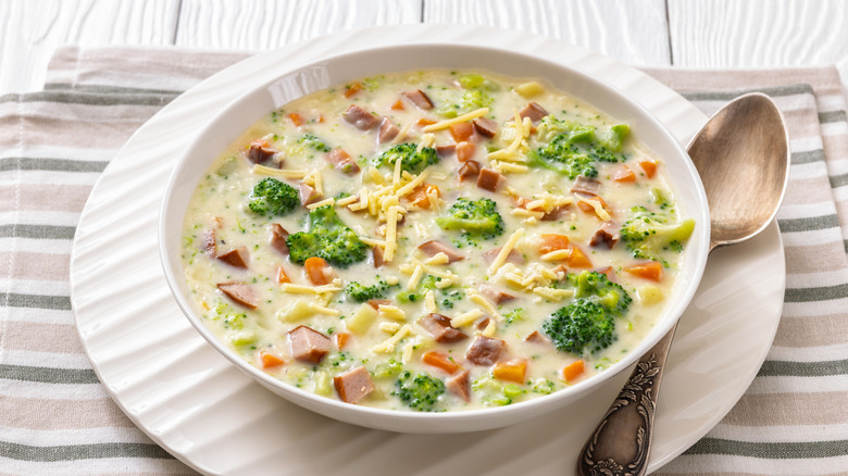 Bowl of creamy broccoli soup with chunks of sausage and shredded cheese