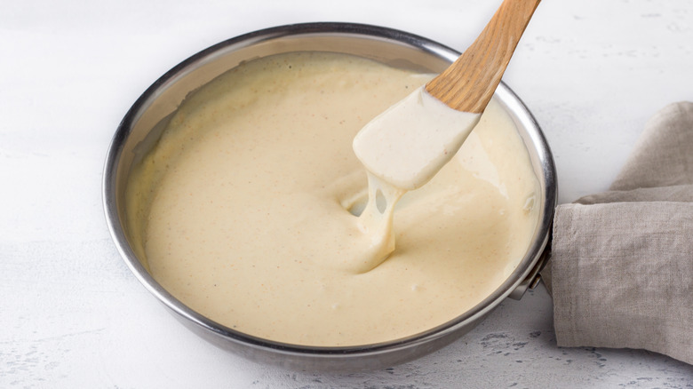 Bowl of creamy cheese sauce with wooden spatula