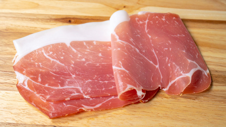Slices of prosciutto on wooden surface