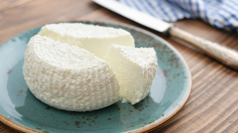 Fresh ricotta cheese on blue plate with wedge sliced out