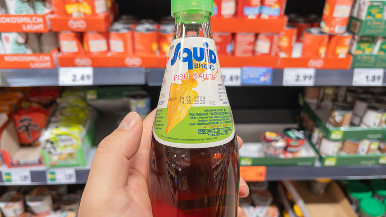 Hand holding bottle of fish sauce in grocery store