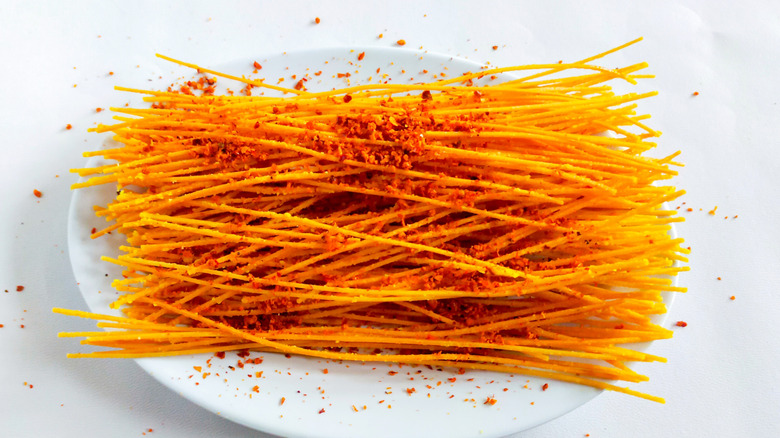 Mie lidi on a white plate sprinkled with red spices