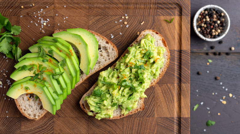Two slices of avocado toast topped with salt and seasonings
