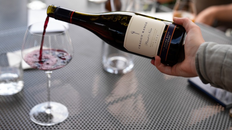 hand pouring red wine in glass
