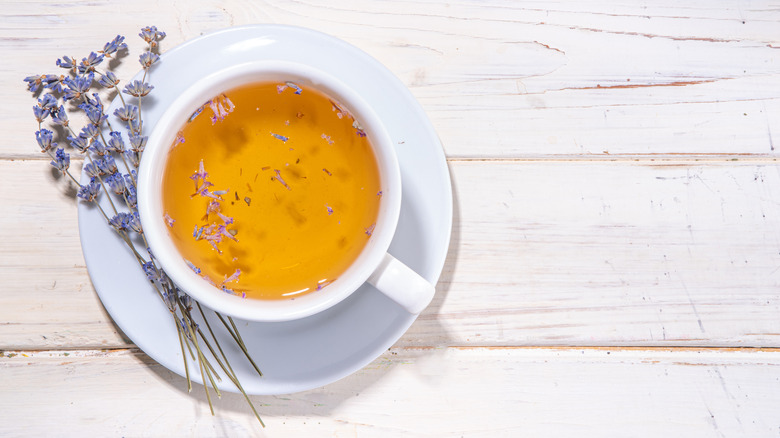 White cup filled with lavender tea against a wooden background