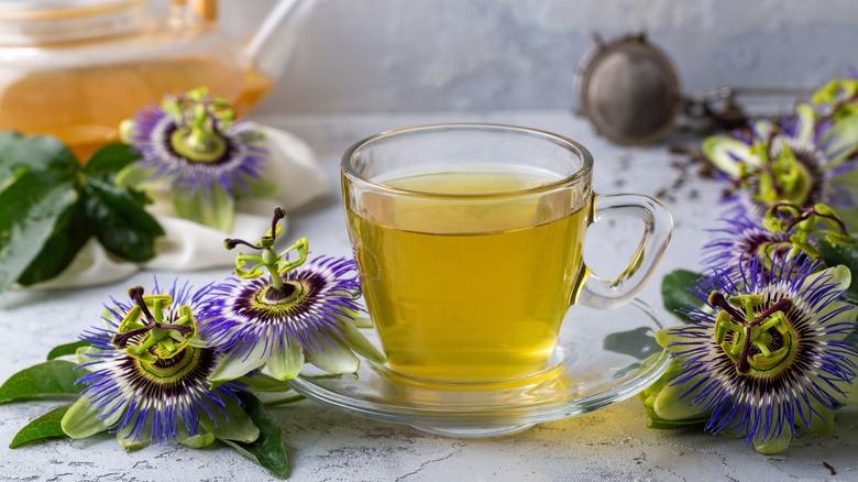 A transparent cup of herbal tea with passionflower beside it