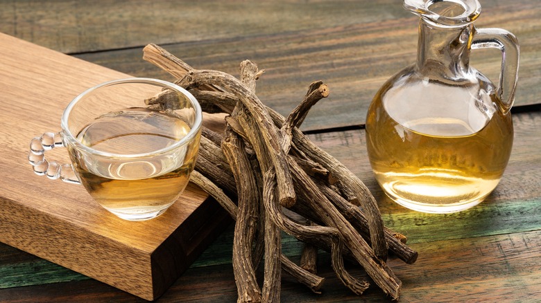 A cup of tea placed next to valerian root on wooden table