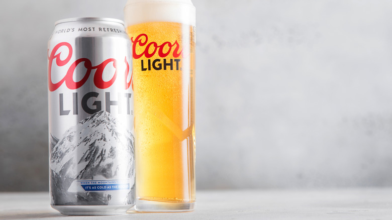 A can and a full glass of Coors Light shown next to each other on a blank background