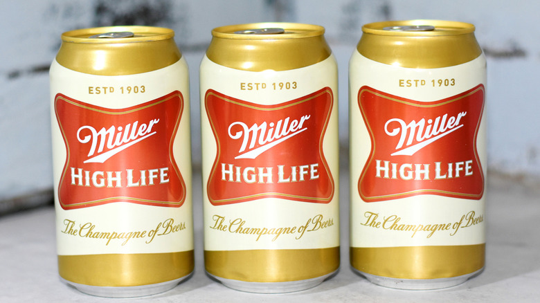 three cans of Cans of Miller High Life Lager Beer against marbled background