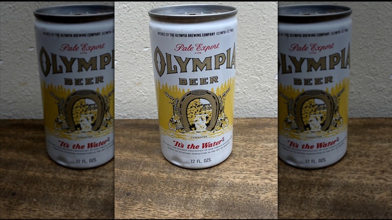 Mirrored image of Vintage Olympia Pull Tab Top Beer Can on wooden surface against white wall