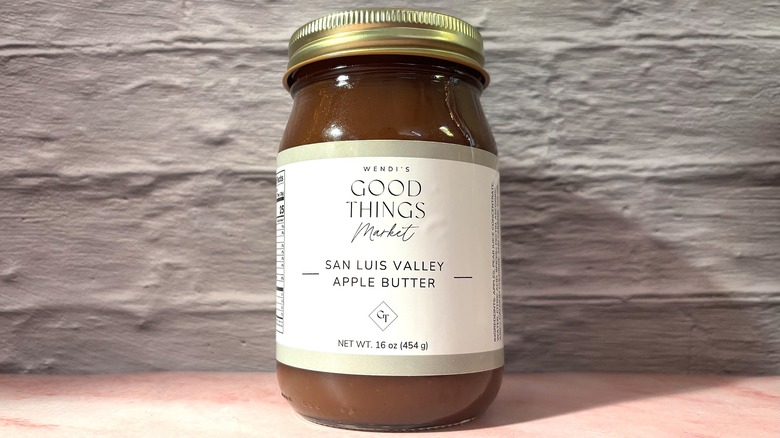 Jar of Wendi's Good Things Market Apple Butter on pink table