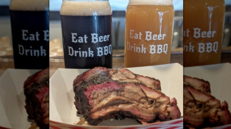 Container of juicy ribs in front of two glasses of beer; one dark and foamy, the other hazy and blonde-colored - both glasses reading "Eat Beer, Drink BBQ"