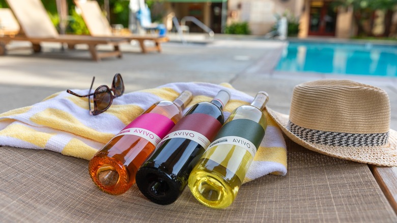 three bottles of wine on blanket near pool