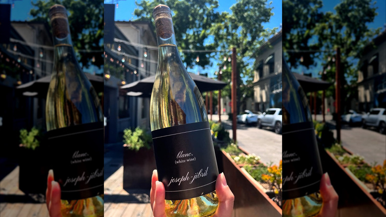 hand holding white wine bottle