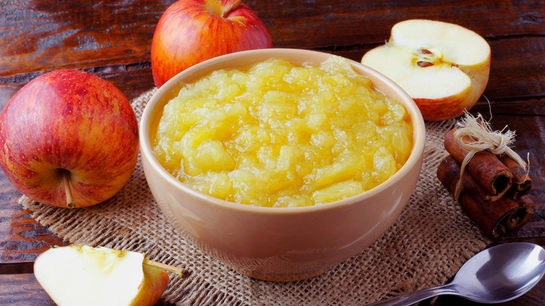 Bowl of homemade applesauce surrounded by apples