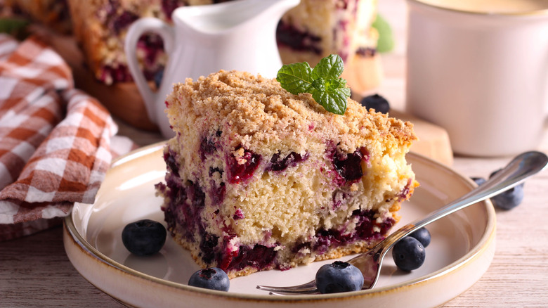 slice of blueberry buckle on a plate with a fork and a mint garnish
