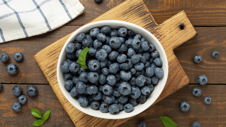 overhead shot of blueberries in a white bowl on a wooden cutting board