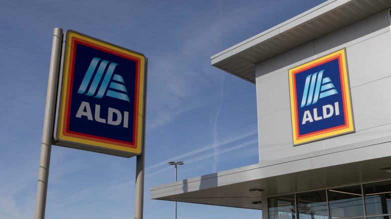 Aldi sign next to Aldi building against blue sky
