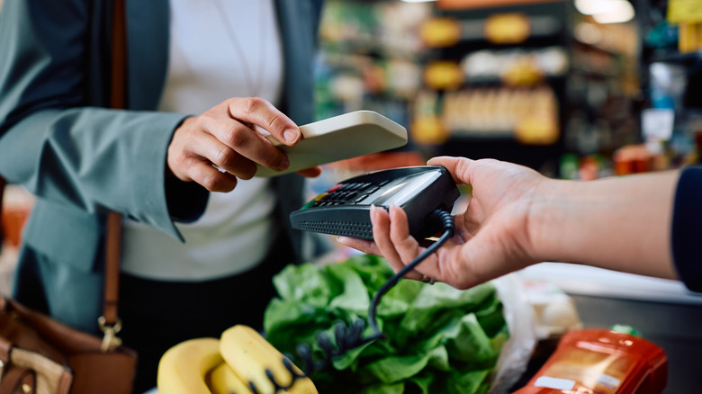 Person paying with credit card at grocery store checkout