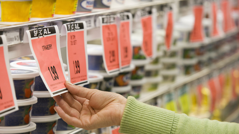 Hand touching red price tag at grocery store