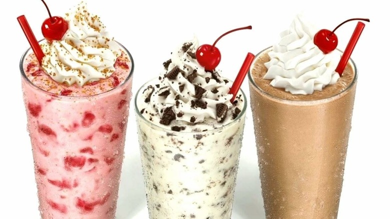 Three Sonic shakes, strawberry cheesecake, oreo cheesecake, and peanut butter, against a white background.
