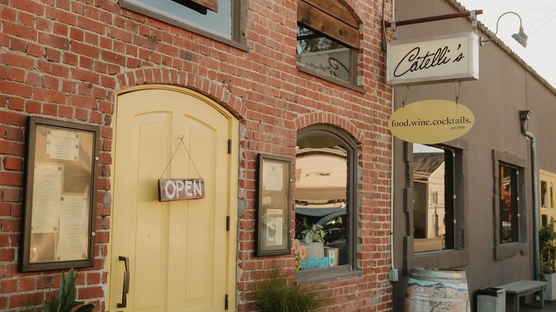 Open sign hangs on the yellow door of Catelli's brick front restaurant