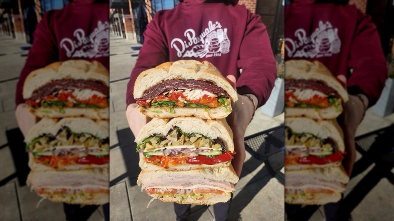 Person wearing a Di Pasquale's top holds a steak of three loaded sandwiches