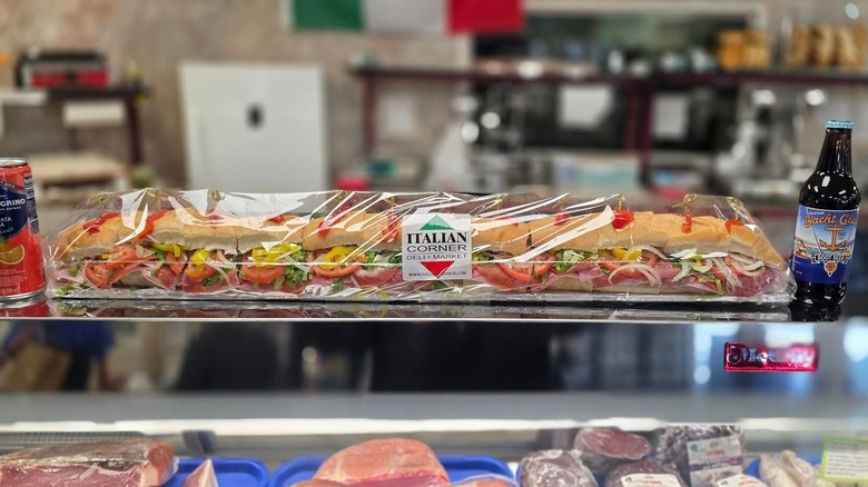 Wrapped 32" sandwich flanked by beverages atop a display case in the Italian Corner
