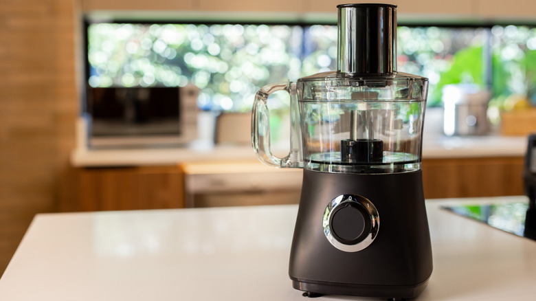 A black food processor on a kitchen counter