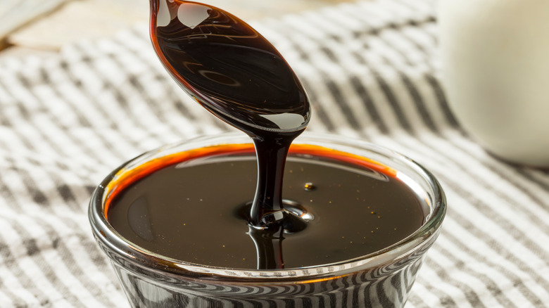 spoon dripping molasses into a glass bowl