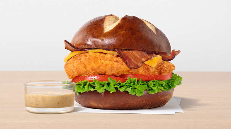 Chick-Fil-A Pretzel Cheddar Club Sandwich next to dish of sauce on wooden table