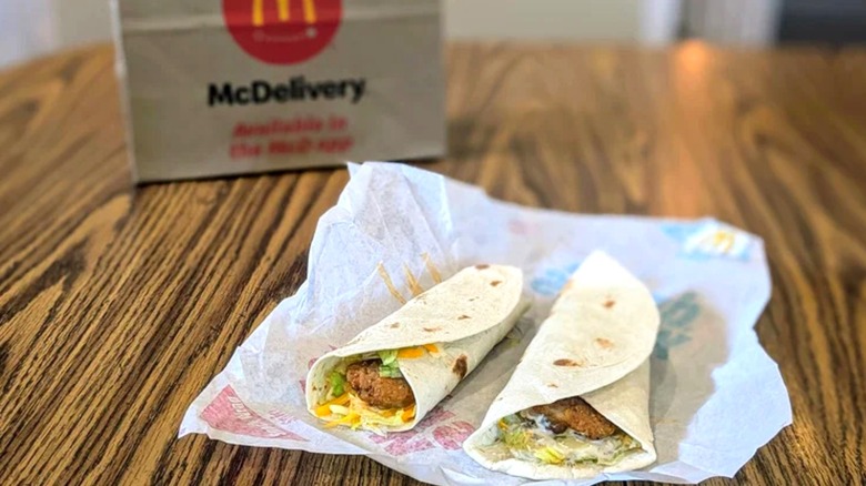 Two McDonald's snack wraps on paper wrapping next to McDonald's deliver bag