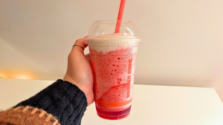 Plastic Burger King cup with a red drink inside and a straw at the top