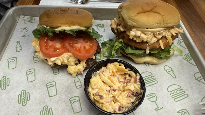 Two burgers filled with pimento cheese spread, alongside the cheese as a dip