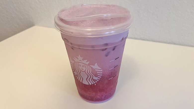 A Starbucks cup with a pink frothy drink inside