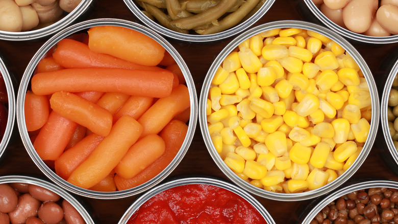 Top down view of opened cans of vegetables, including carrots and corn