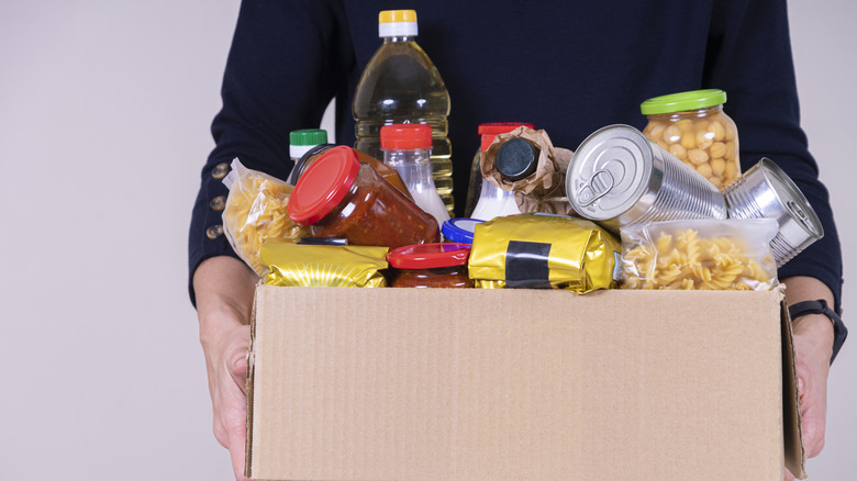 Person holding cardboard box filled with shelf-stable food donations