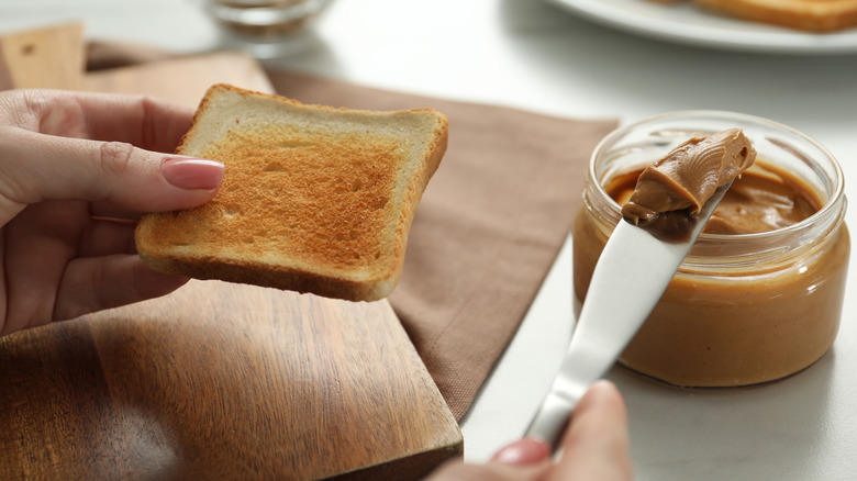 Spreading peanut butter on piece of toast