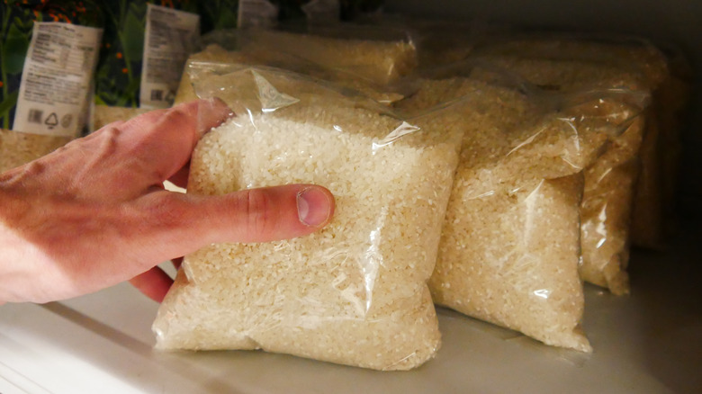 Hand taking bag of dried rice from grocery store shelf