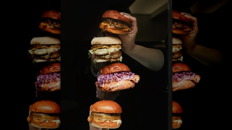 multiple types of sandwiches being held up against a black background
