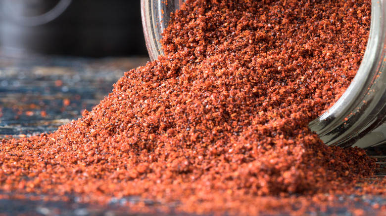 Ground chipotle powder spilling from a jar