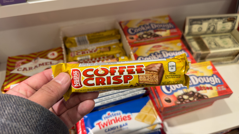 A view of a hand holding a package of Nestle Coffee Crisp chocolate bar, at the store.
