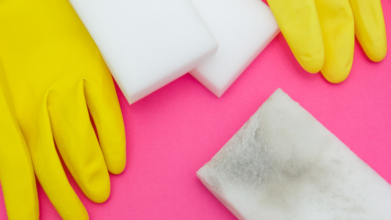 Yellow kitchen gloves with one used and two unused melamine foam sponges