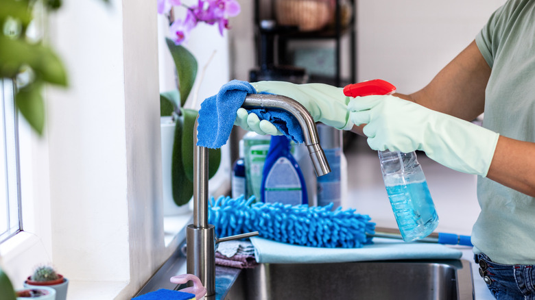 Woman cleaning kitchen faucet wearing kitchen gloves
