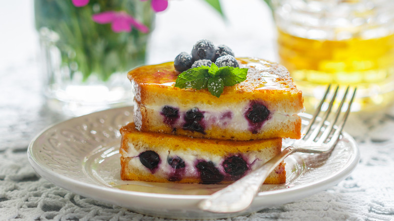 Blueberry and cream cheese-stuffed French toast stacked on plate with fork
