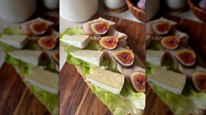 Open-faced turkey, Brie, and fig baguette on wooden cutting board